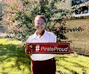 Bridgette smiles holding a Pirate Proud sign