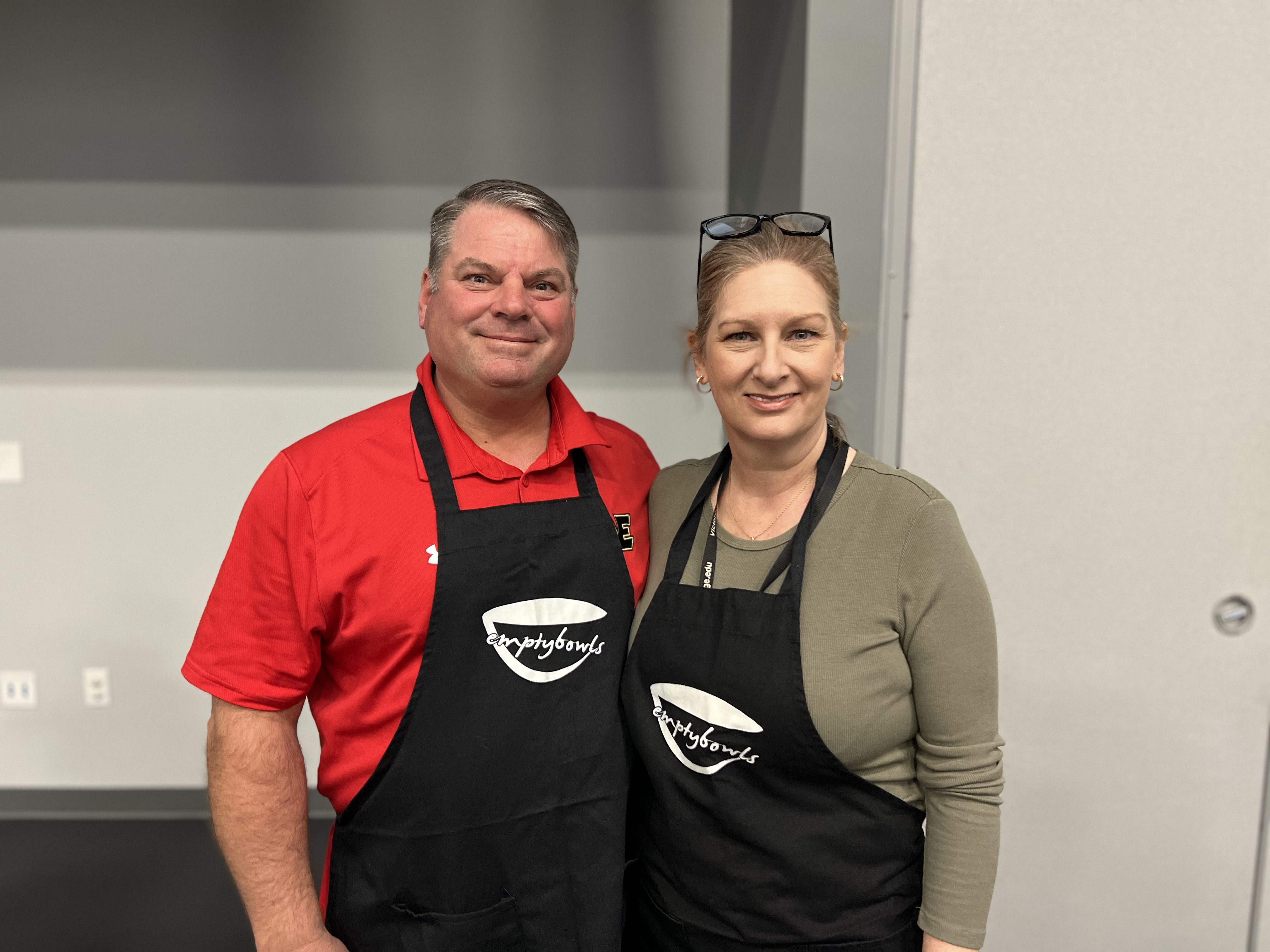 Dr. Jennifer Kent and Doug Kent wear black empty bowls aprons