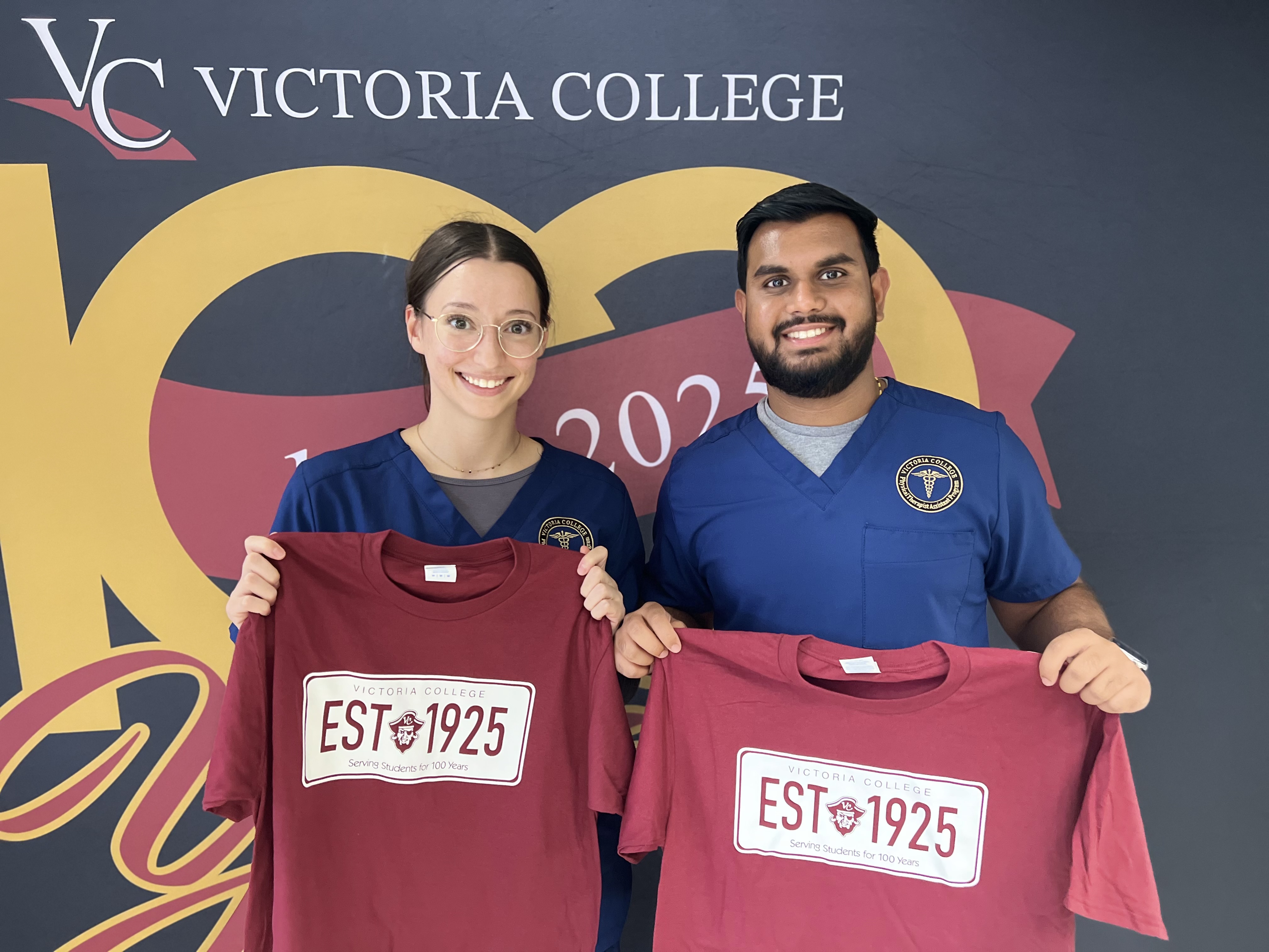 Two Physical Therapy Assistant students hold up their free Victoria College t-shirts